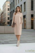 Woman wearing a beige dress walking on a city street with buildings in the background